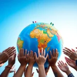 Hands reaching towards a globe representing worldwide unity and diversity.