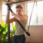Young athlete using a pull-up assist band for an effective workout in a bright gym setting.